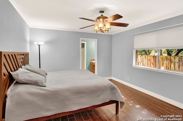 bedroom featuring dark hardwood / wood-style flooring, ensuite bath, crown molding, and ceiling fan