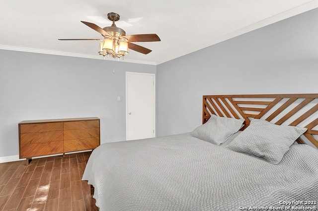 bedroom with dark hardwood / wood-style floors, ornamental molding, and ceiling fan