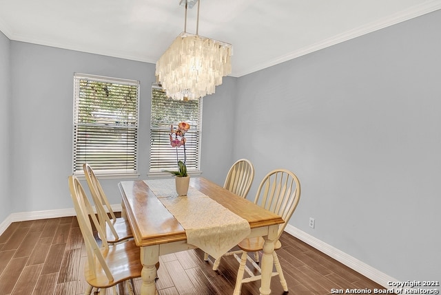 dining space with hardwood / wood-style flooring, a notable chandelier, and crown molding