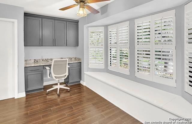 office space featuring ceiling fan, built in desk, hardwood / wood-style floors, and plenty of natural light