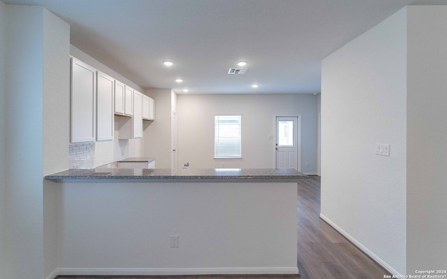 kitchen featuring dark wood-type flooring, white cabinets, kitchen peninsula, and stone counters