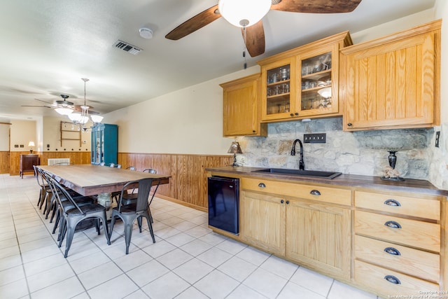 kitchen featuring ceiling fan, tasteful backsplash, sink, black dishwasher, and light tile patterned floors