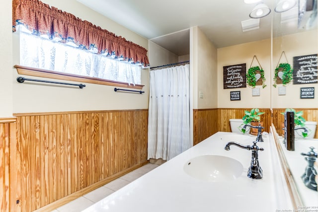 bathroom featuring tile patterned flooring, a healthy amount of sunlight, toilet, and sink