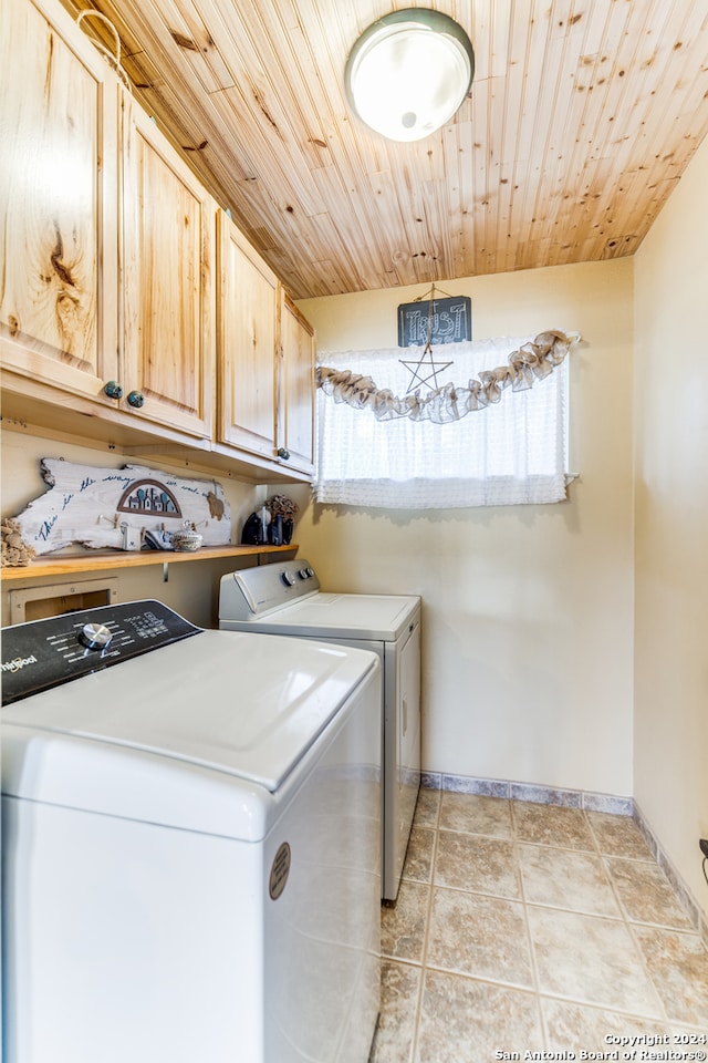 washroom featuring light tile patterned floors, washing machine and clothes dryer, wood ceiling, and cabinets