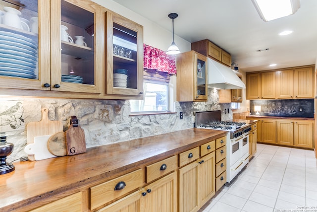 kitchen featuring range with two ovens, hanging light fixtures, custom range hood, light tile patterned floors, and backsplash