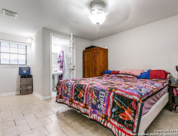 bedroom with connected bathroom, ceiling fan, and light tile patterned floors