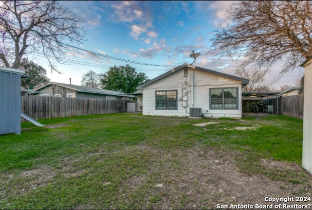 back of house featuring central AC and a yard