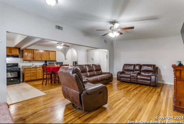 living room featuring beamed ceiling, ceiling fan, and light wood-type flooring