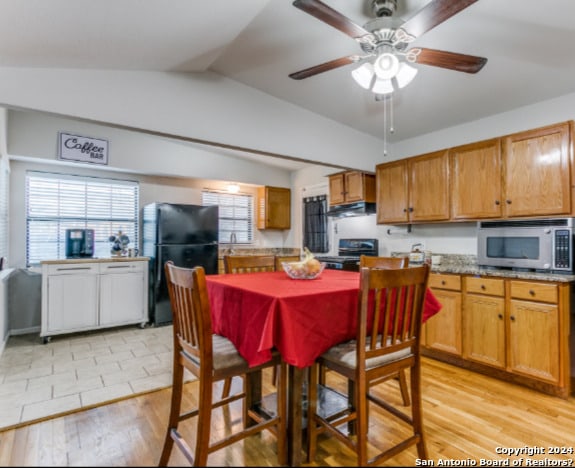 kitchen featuring light wood-type flooring, extractor fan, vaulted ceiling, ceiling fan, and black appliances