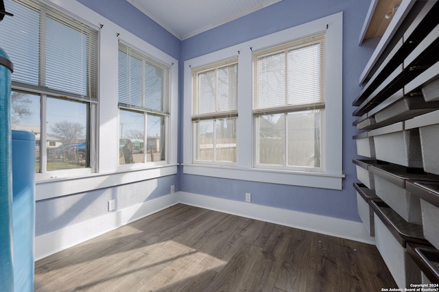 empty room with a healthy amount of sunlight, crown molding, and dark wood-type flooring