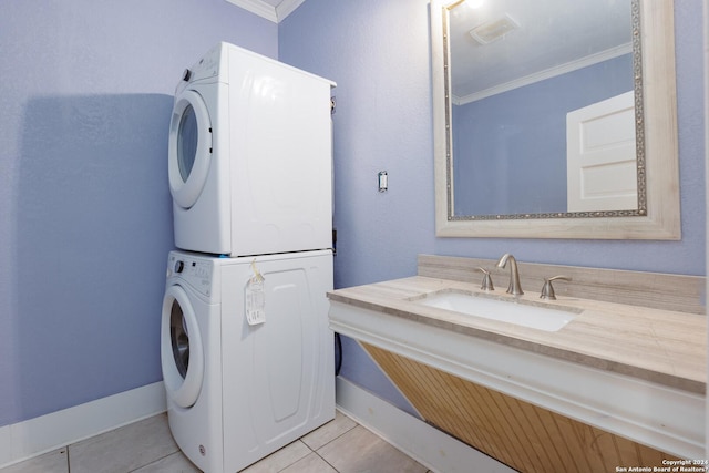 washroom featuring light tile patterned flooring, stacked washing maching and dryer, ornamental molding, and sink