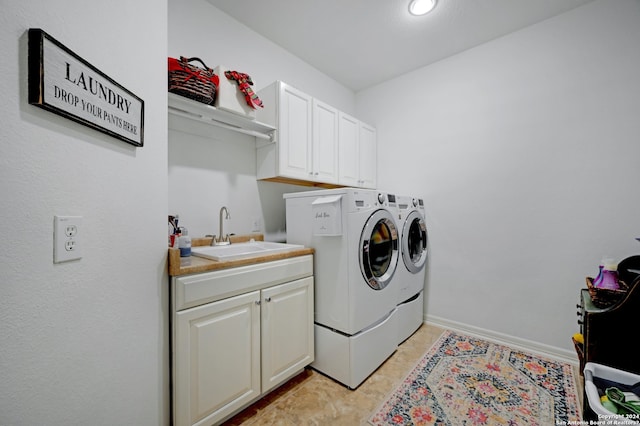 laundry area with cabinets, washer and clothes dryer, sink, and light tile patterned floors