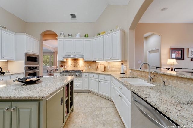 kitchen featuring light tile patterned floors, light stone counters, stainless steel appliances, sink, and tasteful backsplash