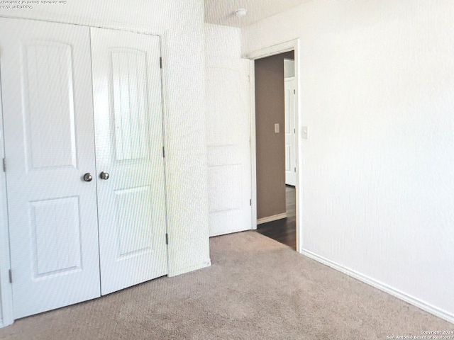 unfurnished bedroom featuring a closet and dark colored carpet