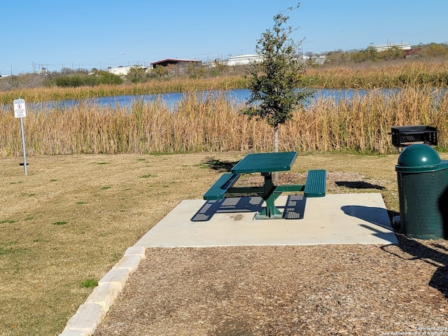 view of property's community featuring a yard, a water view, and a patio area