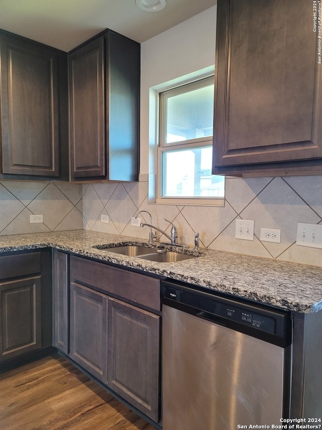 kitchen with light stone counters, stainless steel dishwasher, dark hardwood / wood-style floors, sink, and dark brown cabinets