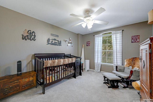 carpeted bedroom featuring a crib and ceiling fan