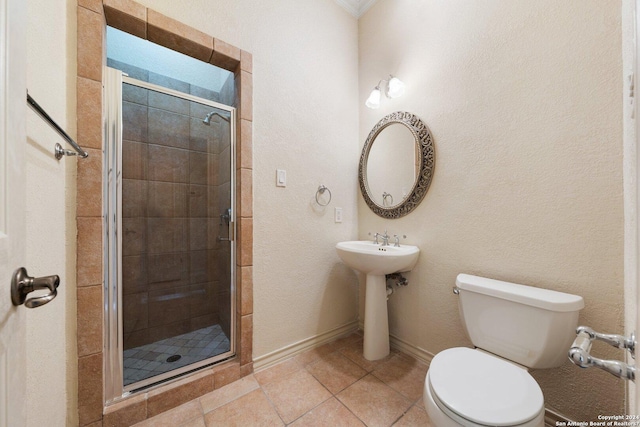 bathroom featuring a shower stall, baseboards, toilet, tile patterned floors, and a sink