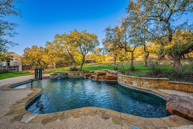 view of pool featuring a pool with connected hot tub and fence