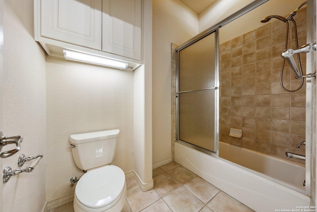 full bath featuring tile patterned floors, baseboards, toilet, and bath / shower combo with glass door