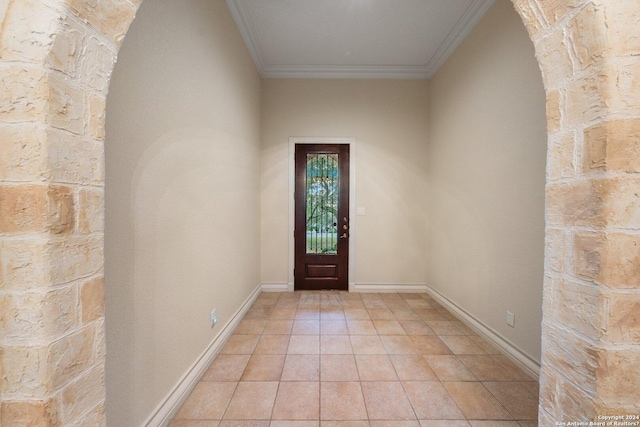 entryway with light tile patterned floors, baseboards, arched walkways, and ornamental molding