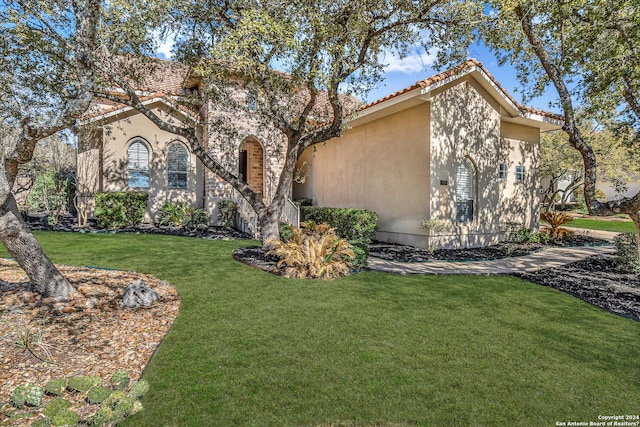 view of front of home featuring stucco siding, a front yard, and a tiled roof