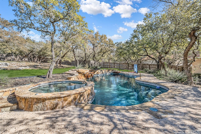 view of pool with a fenced backyard and a pool with connected hot tub