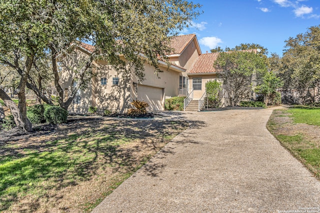 exterior space with stucco siding, an attached garage, driveway, and a tile roof