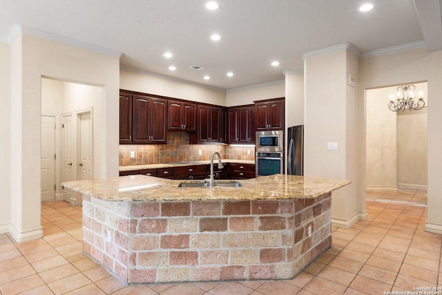 kitchen featuring crown molding, a center island with sink, decorative backsplash, appliances with stainless steel finishes, and a sink