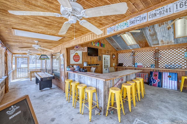 bar with ceiling fan, vaulted ceiling with skylight, and concrete flooring