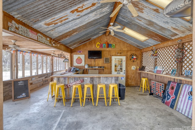 kitchen featuring kitchen peninsula, ceiling fan, lofted ceiling, and concrete flooring