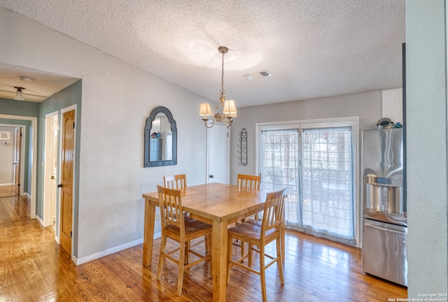 dining room with a textured ceiling, an inviting chandelier, and wood-type flooring