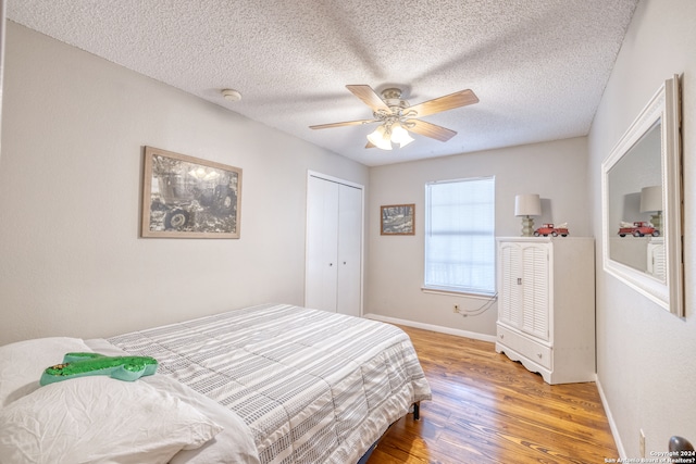 bedroom featuring light wood-type flooring, ceiling fan, a closet, and a textured ceiling