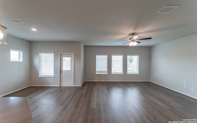 unfurnished living room with a textured ceiling, a healthy amount of sunlight, ceiling fan, and dark hardwood / wood-style flooring