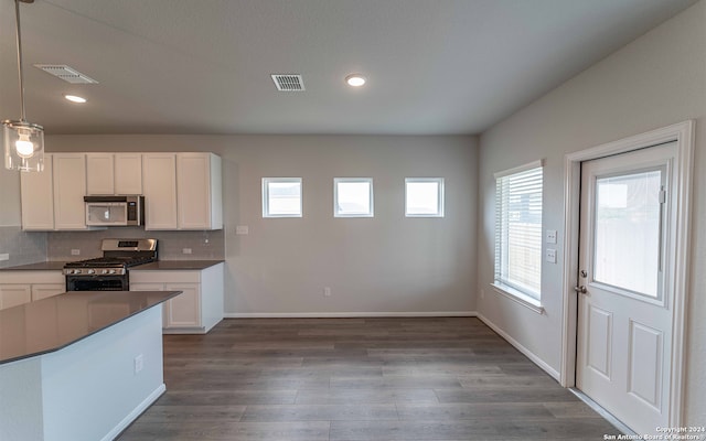 kitchen featuring appliances with stainless steel finishes, tasteful backsplash, dark wood-type flooring, and pendant lighting