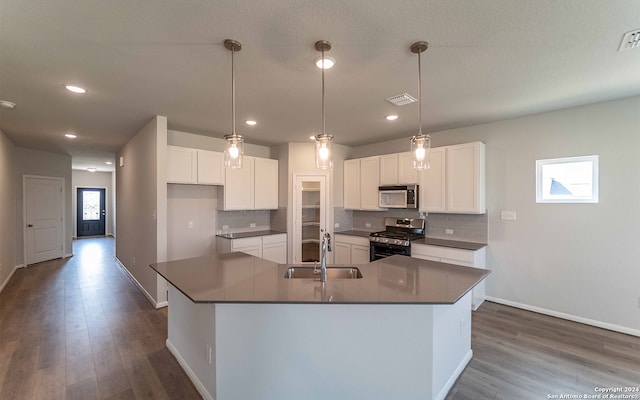 kitchen featuring a kitchen island with sink, white cabinetry, stainless steel appliances, sink, and dark wood-type flooring