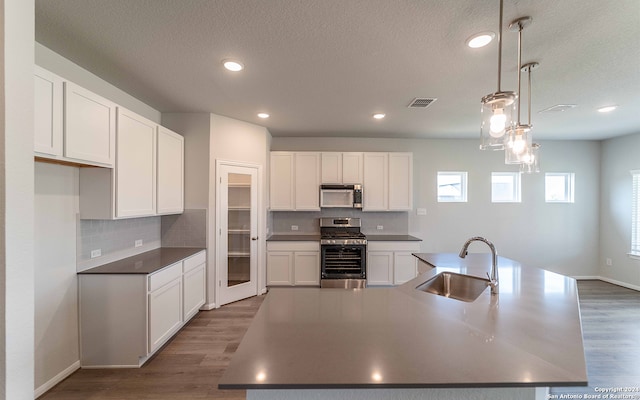 kitchen featuring appliances with stainless steel finishes, dark hardwood / wood-style flooring, sink, and hanging light fixtures