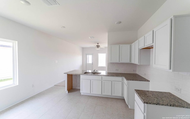 kitchen with dark stone counters, a sink, a ceiling fan, and backsplash