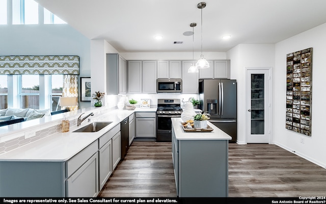 kitchen with dark hardwood / wood-style floors, stainless steel appliances, gray cabinetry, pendant lighting, and sink