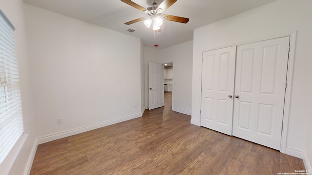 unfurnished bedroom with ceiling fan, a closet, and dark wood-type flooring