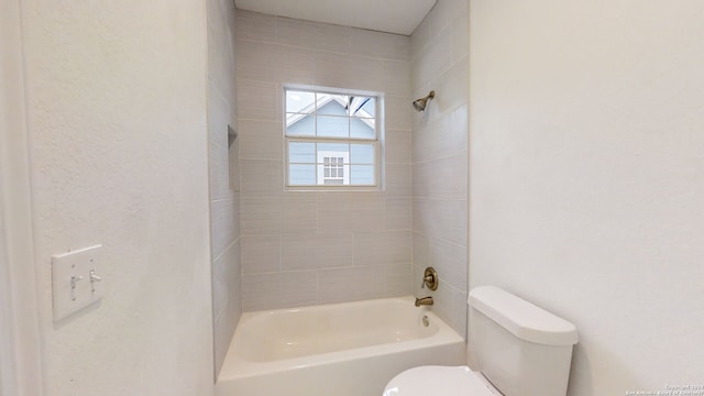 bathroom with toilet and tiled shower / bath