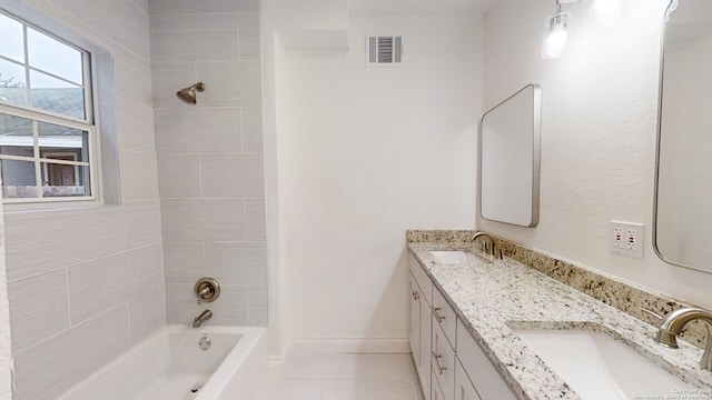 bathroom featuring double sink vanity, tile flooring, and tiled shower / bath