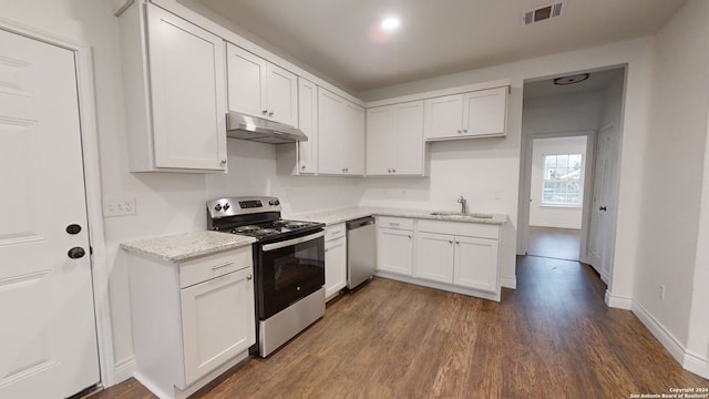 kitchen with white cabinets, dark hardwood / wood-style floors, light stone counters, and stainless steel appliances