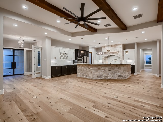 kitchen with ceiling fan, a spacious island, light hardwood / wood-style floors, and pendant lighting