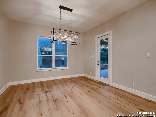 empty room with a notable chandelier and light wood-type flooring