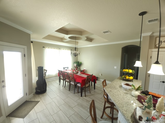 dining area with a notable chandelier, ornamental molding, and a raised ceiling