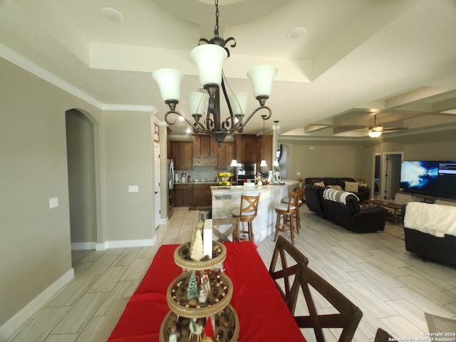 dining space with a tray ceiling, ornamental molding, and ceiling fan with notable chandelier