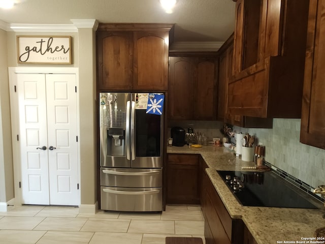 kitchen featuring stainless steel fridge, ornamental molding, backsplash, black electric cooktop, and light stone countertops