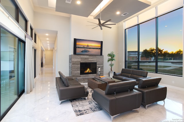 tiled living room featuring a high ceiling, ceiling fan, and a fireplace