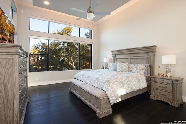 bedroom with a towering ceiling, ceiling fan, and dark hardwood / wood-style floors